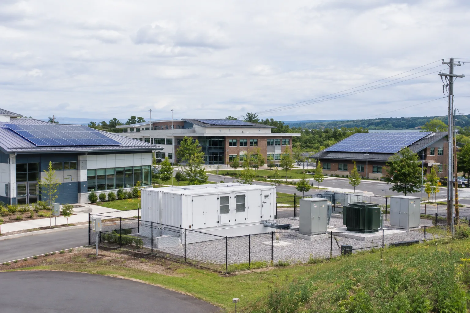 Panneaux solaires et équipement de stockage alimentant un ensemble de bâtiments raccordé au réseau électrique.